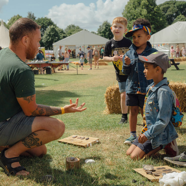 Three children listening to an adult outdoors