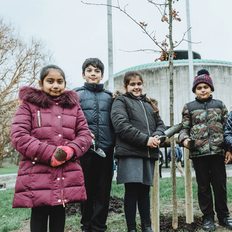 Four children standing next to a tree