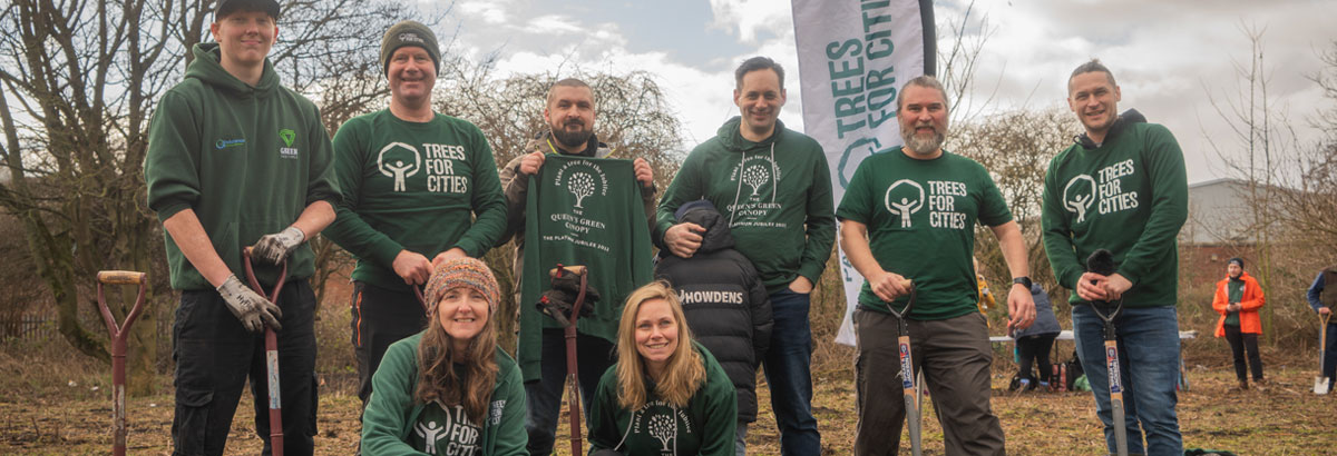 Eight people all wearing Trees For Cities shirts standing in a field