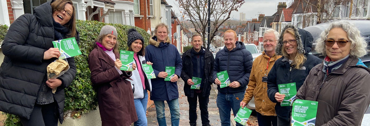 Group of people standing in a street holding fliers promoting making the area greener